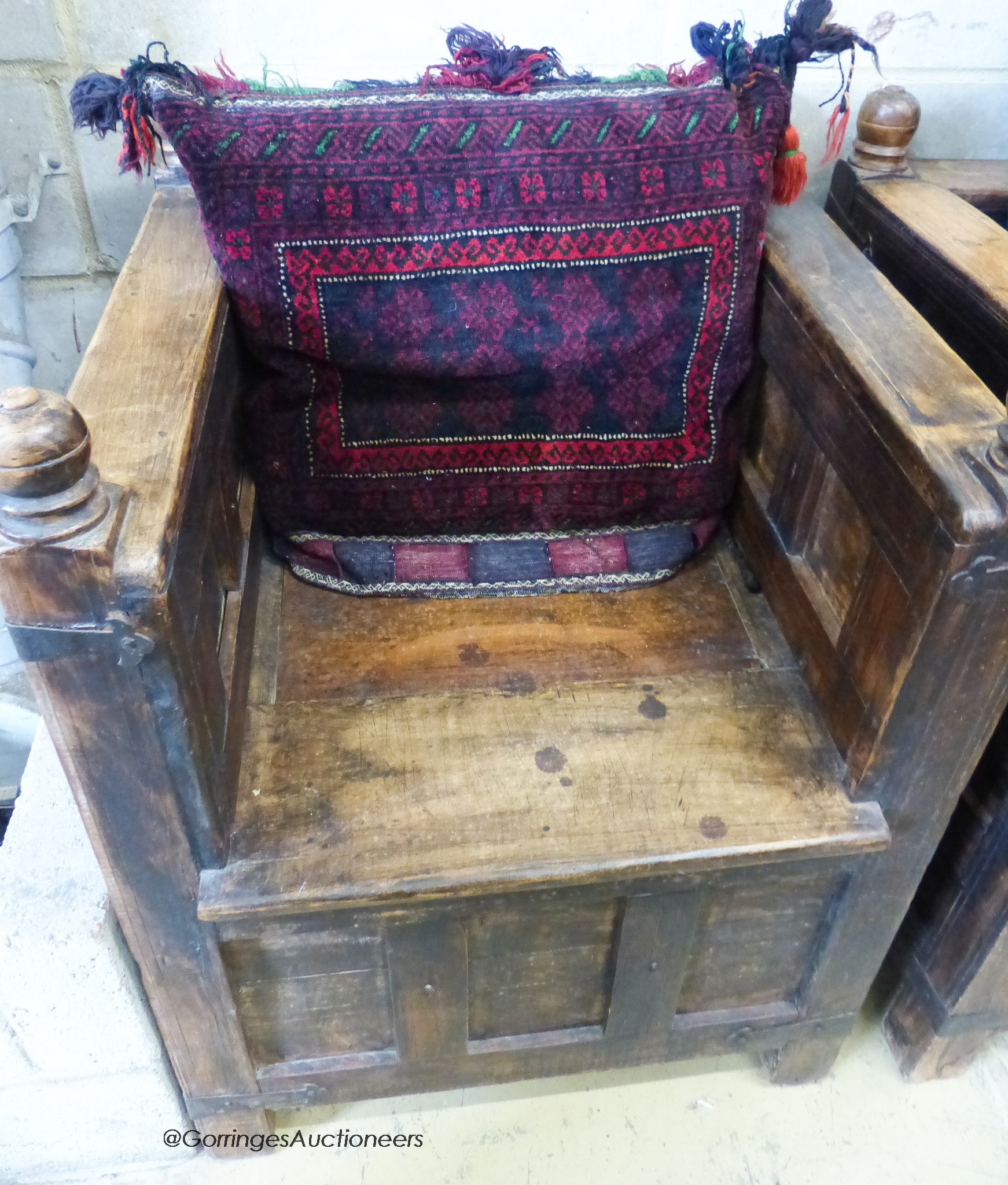 An Indian iron mounted, paneled hardwood hinged box seat bench and two chairs, all with Caucasian/Turkish cushions. Bench - W-138cm, D-69, H-91cm.